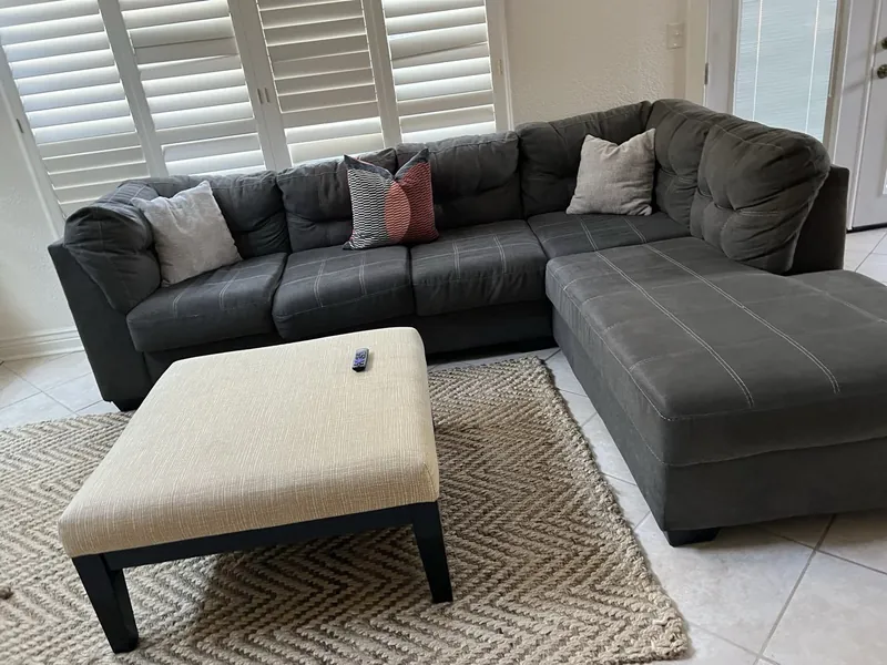Sunroom before: a gray sectional and a cream ottoman