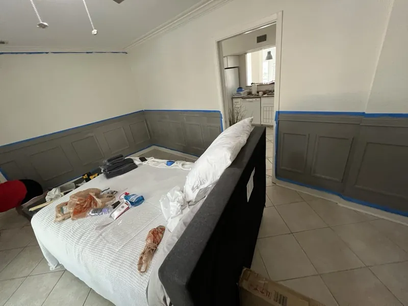 Wainscot room before: gray panelling partway through painting
