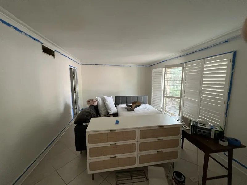 Longhorn room before: white walls taped for painting and a rattan dresser
