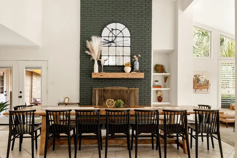 Fireplace wall after: green painted brick, an arched mirror and a long farm table