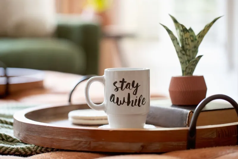 A Stay Awhile mug on a wooden tray