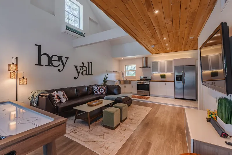 Game room in 2023: black hey y’all letters over a leather sectional