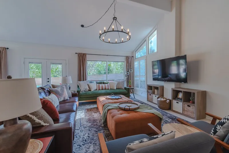 Living room after: leather sofas, an orange ottoman and a black chandelier
