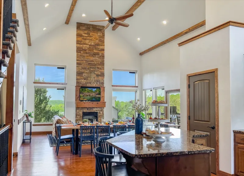 Great room after: white walls, blue chairs at the island and a stone fireplace