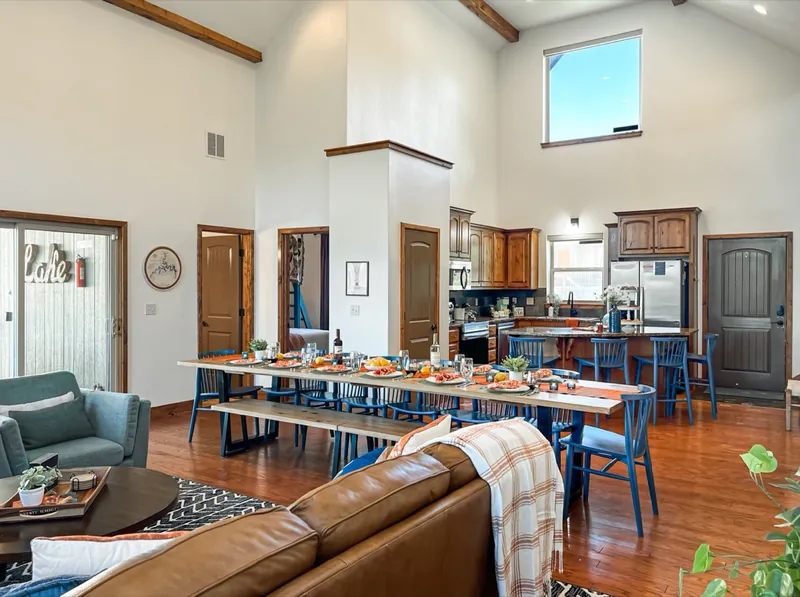 Dining after: long table with blue chairs looking toward the kitchen