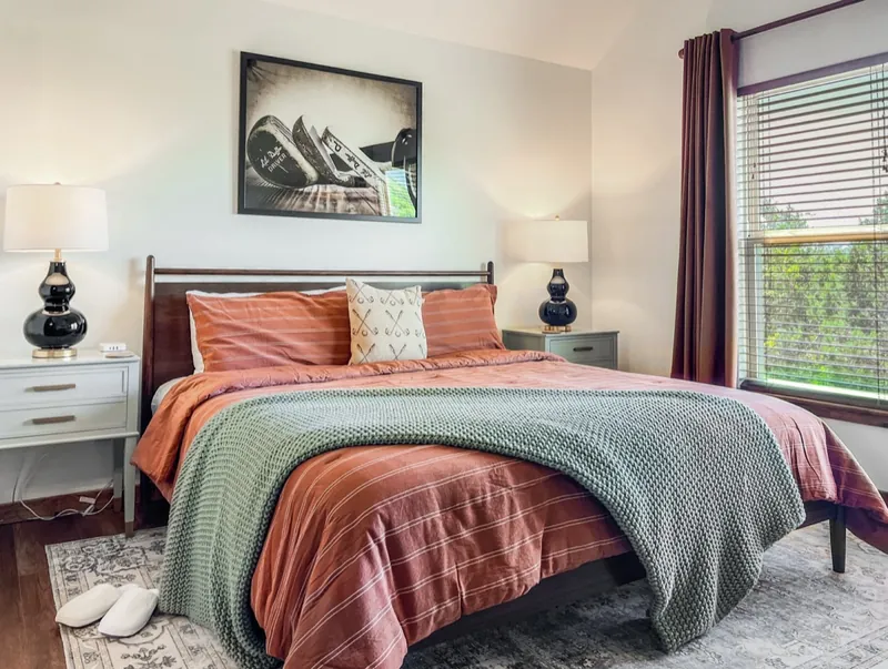 Queen room after: rust and sage bedding with black-and-white art