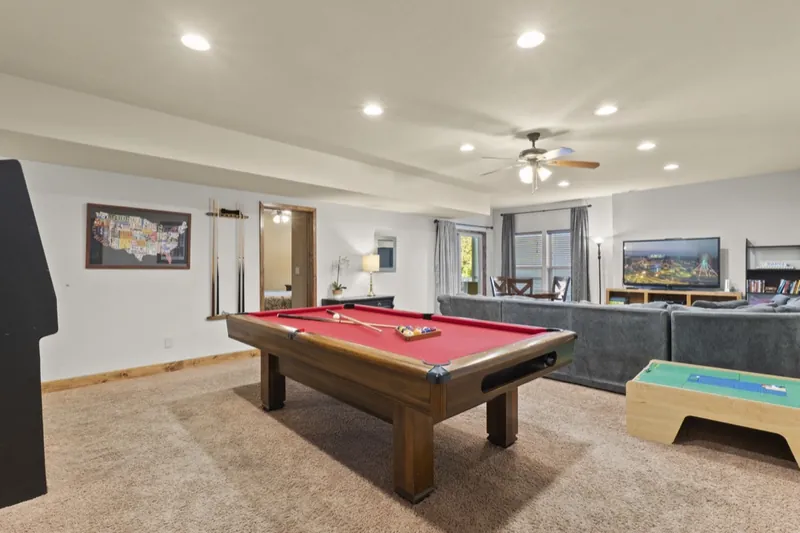 Rec room before: carpet, a red pool table and a grey sectional