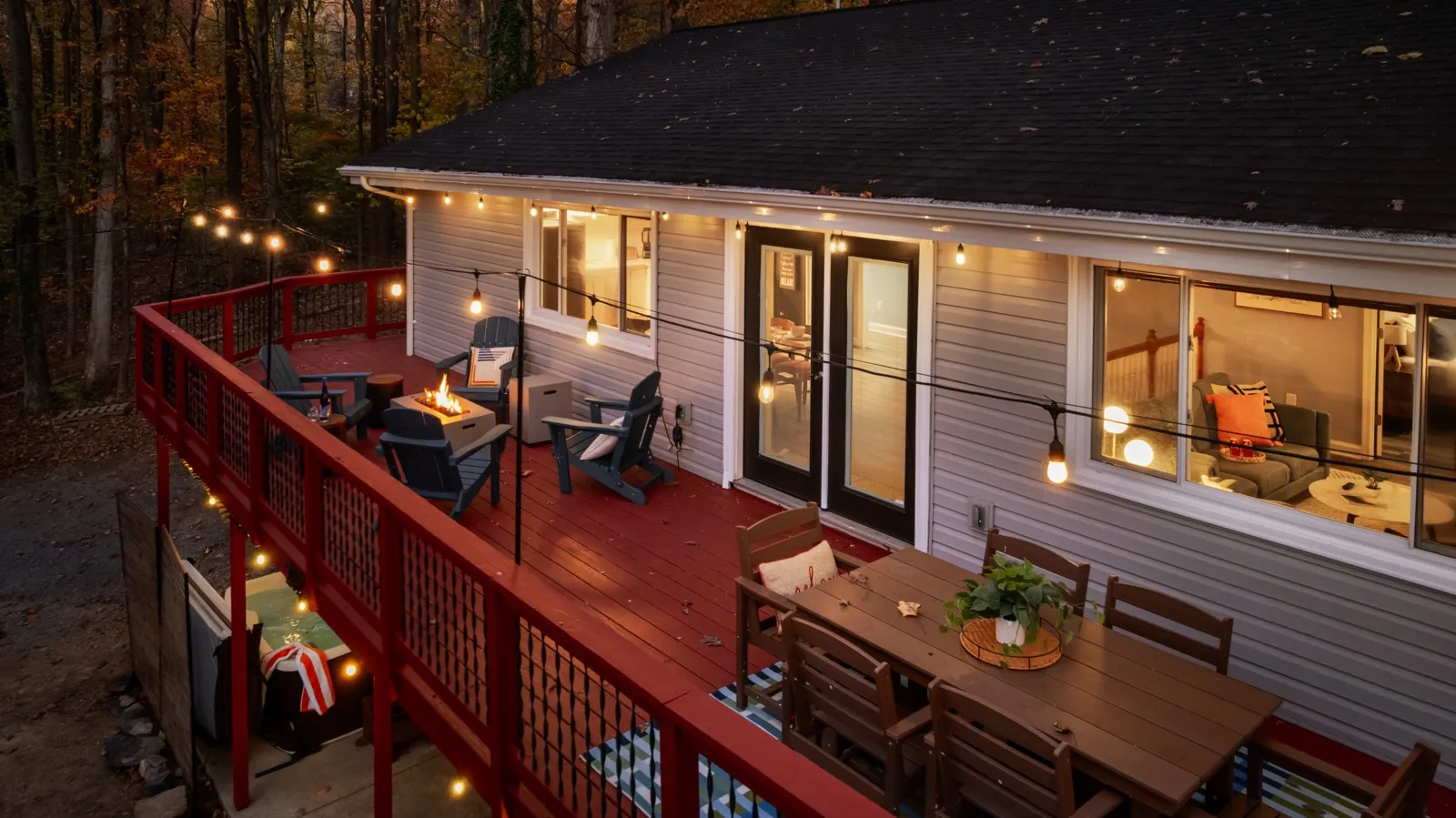 The upper deck at dusk from above: string lights, fire table and dining set