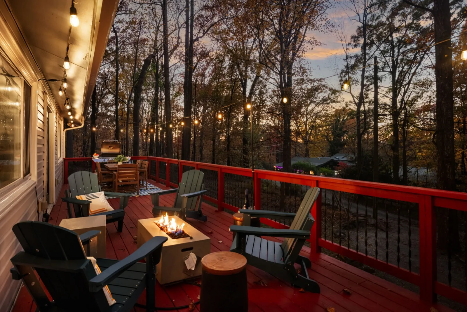 Upper deck after: navy Adirondack chairs around a fire table at dusk