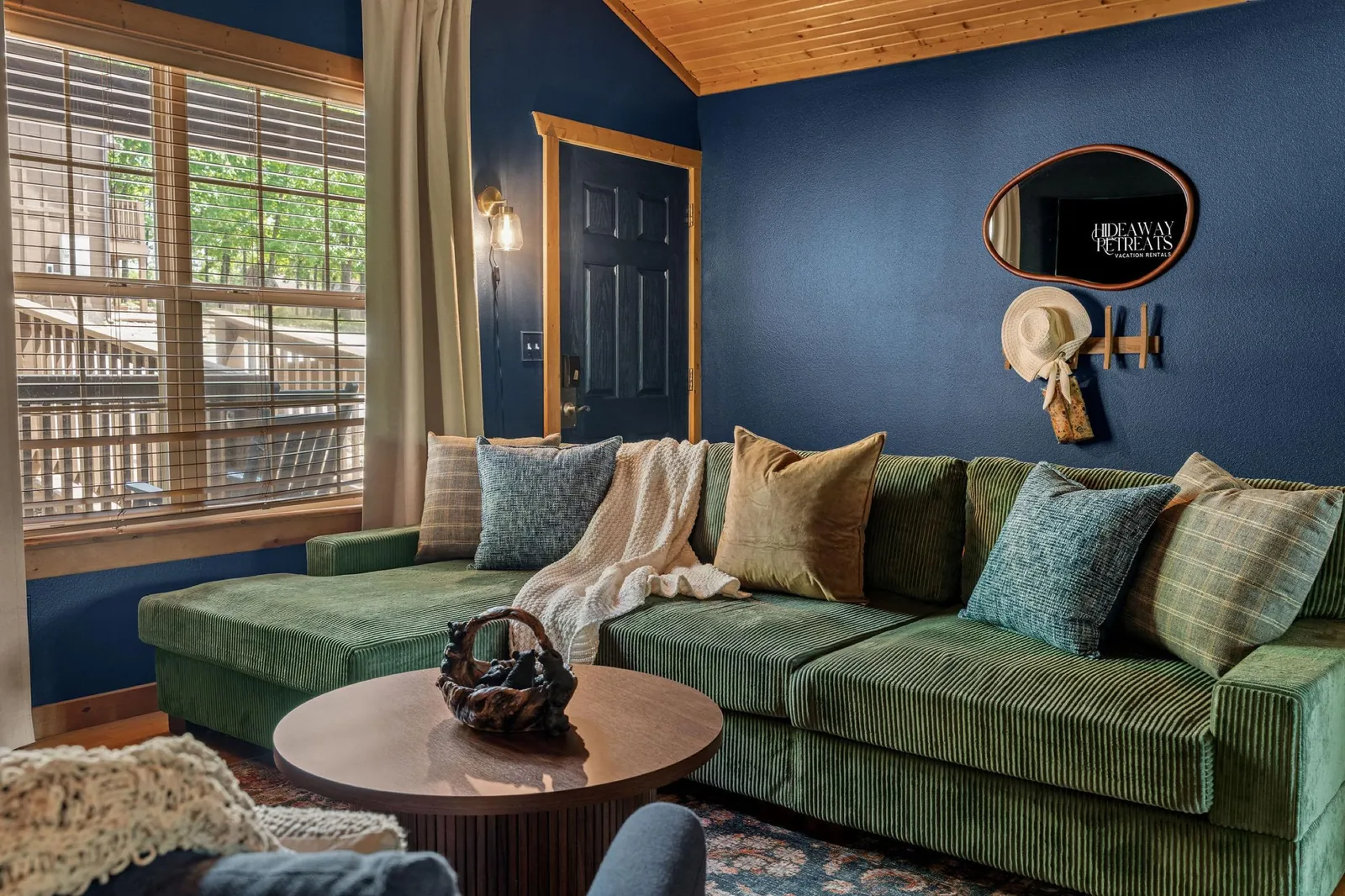 Little Bear Cabin living room: a green corduroy sectional against deep navy walls