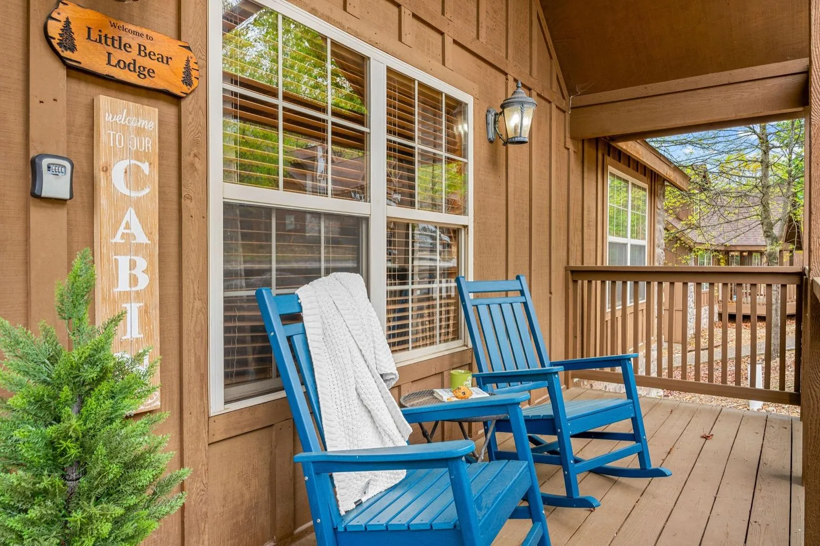Front porch after: blue rockers, a Little Bear Lodge sign and greenery