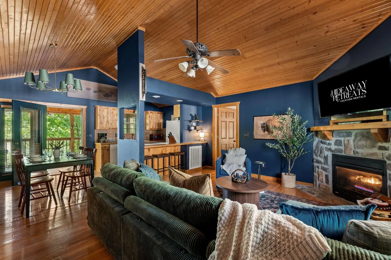 Living and dining after: navy walls, a green sectional and a black dining table