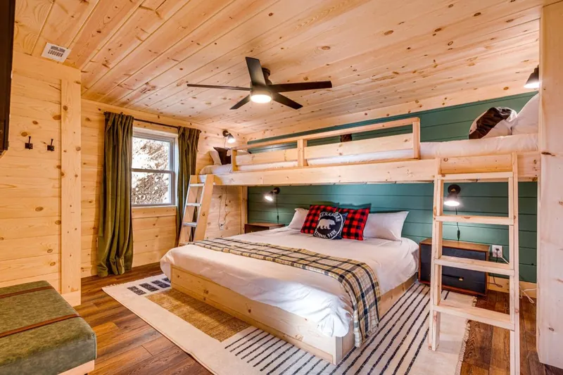Finished bunkhouse: two Twin XL bunks over a king, forest-green shiplap and plaid bedding