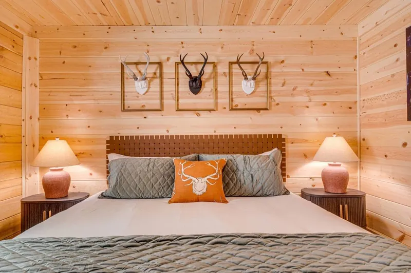 Antler lodge bedroom with a woven headboard, antler trio and sage quilt